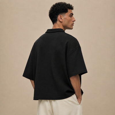 Polo El Beida gaufré noire porté de dos, coupe boxy épaules tombantes