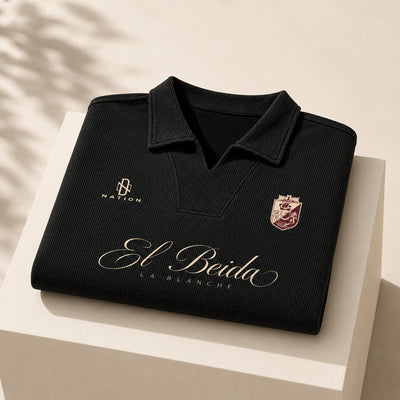 Polo El Beida gaufré noir plié, script écru visible